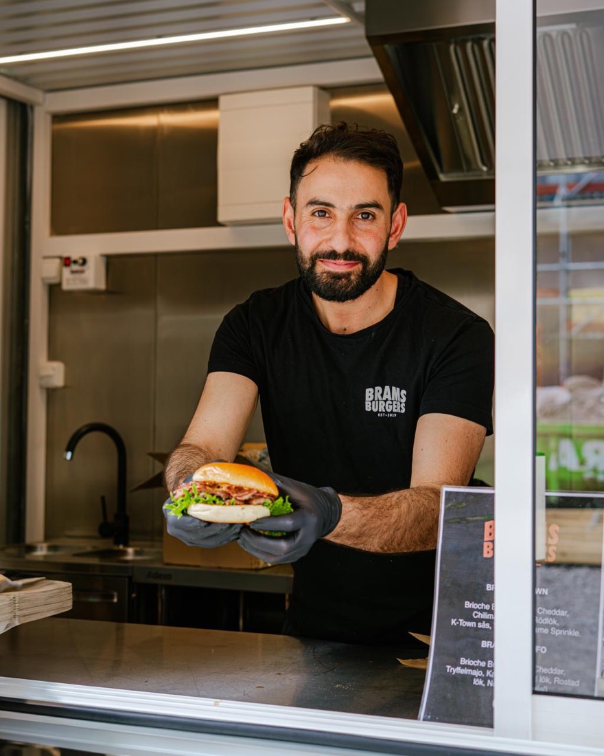 BRAMS food truck-personal lämnar ut en nylagad burgare genom luckan